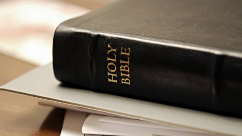 A Bible lying on a table on top of paper.