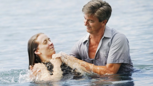 A man baptizing a woman after being fully submersed in the water.
