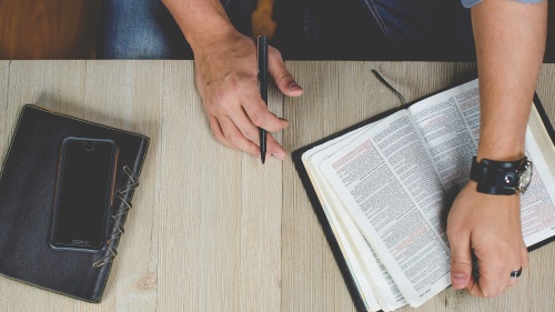 A man studying a Bible on a table.