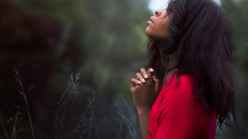 A woman praying while outside.