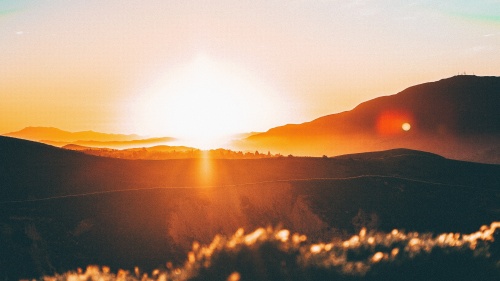 A sun setting over hills.