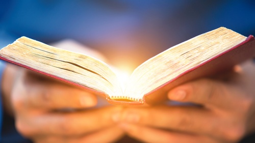 A open Bible emitting rays of light.