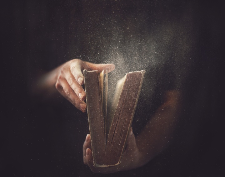 A person opening a dusty Bible.
