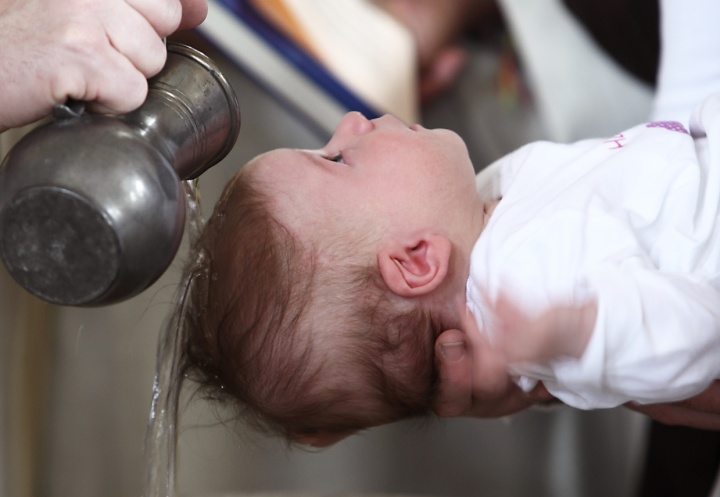 A baby being sprinkled with water.