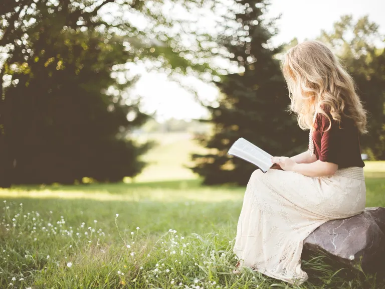 woman sitting in a meadow and reading