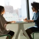 Dos personas conversando, sentadas una frente a la otra