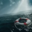 A life preserver ring floating in rough waters with sunlight coming through the clouds.