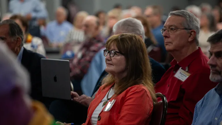 people seated indoors and listening to a presentation