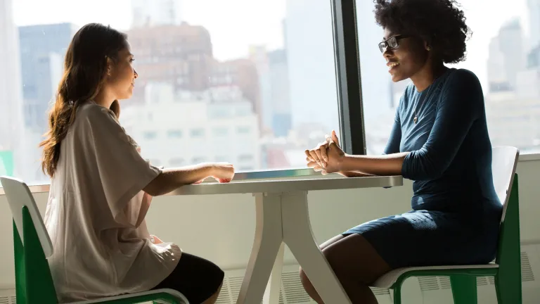Dos personas conversando, sentadas una frente a la otra