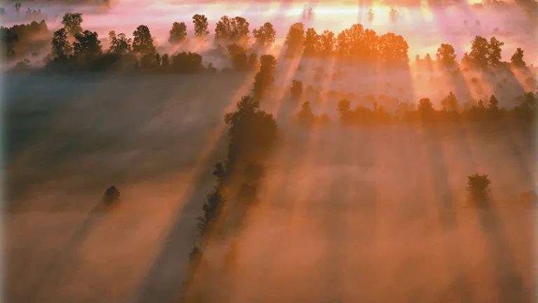 A sunrise over a field with a morning mist.