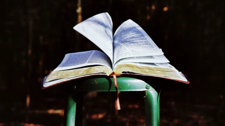 An open Bible on a metal stool.