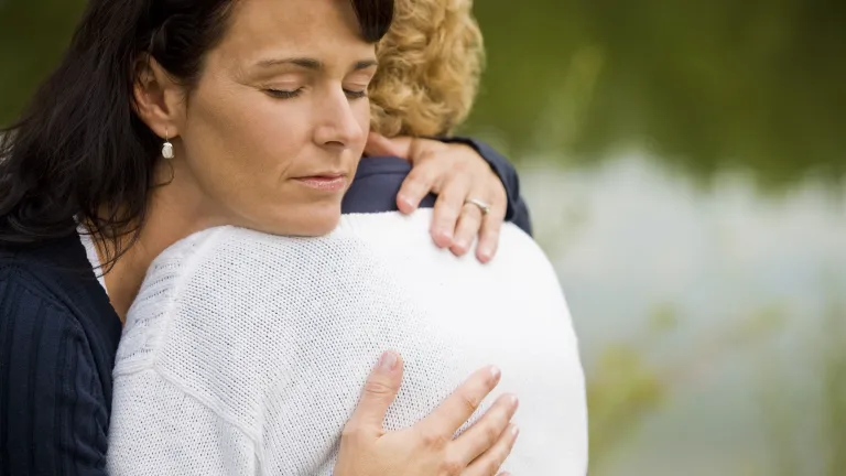 A woman hugging a grieving woman.