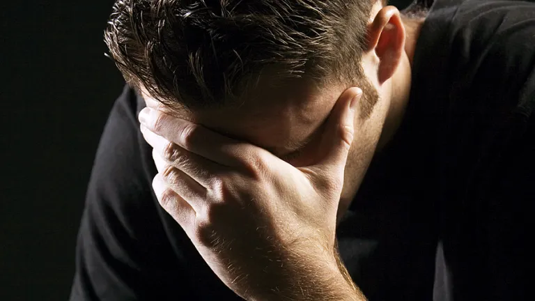 A young man holding his head with hands as in sorrow or remorse.