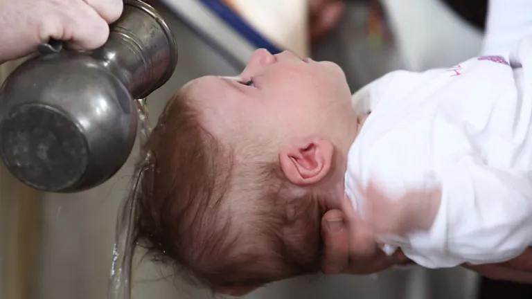 Baptism must wait until we are mature enough to understand repentance and the magnitude of committing one’s life to following God. A baby being sprinkled with water.