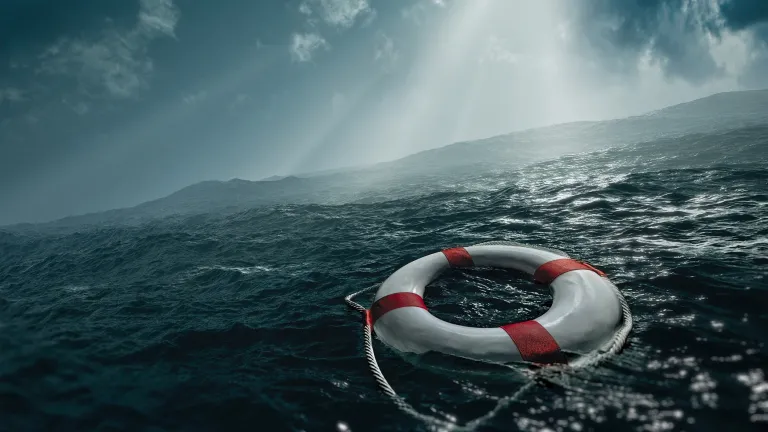 A life preserver ring floating in rough waters with sunlight coming through the clouds.