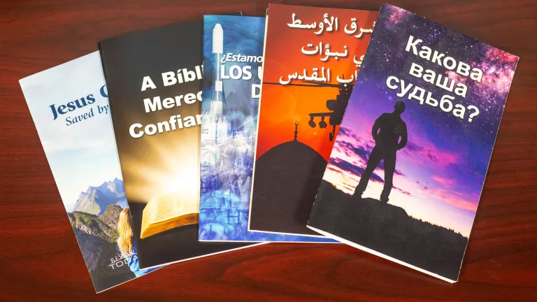 Five UCG booklets in a variety of languages on a wooden surface