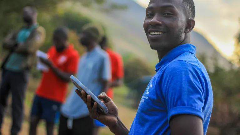 Man smiling at camera holding phone
