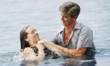 A man baptizing a woman after being fully submersed in the water.