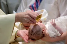 A baby being sprinkled with water.