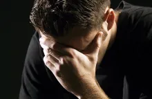 A young man holding his head with hands as in sorrow or remorse.