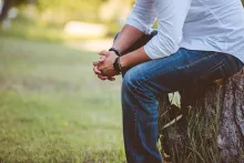 A man sitting on log praying.