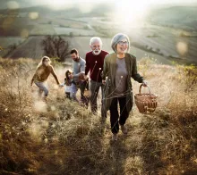 A multi generation family walking in a field.