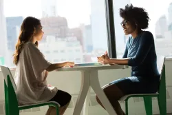 Dos personas conversando, sentadas una frente a la otra