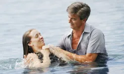 A man baptizing a woman after being fully submersed in the water.