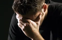 A young man holding his head with hands as in sorrow or remorse.