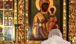 Woman praying to Mother Mary and baby Jesus painting.